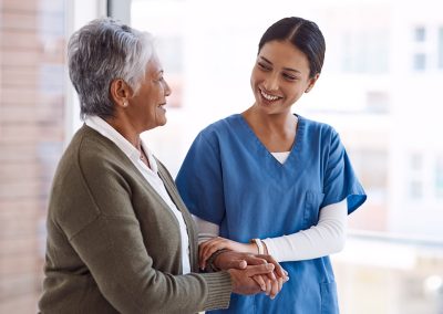 Nurse smiling and walking arm in arm with a female resident